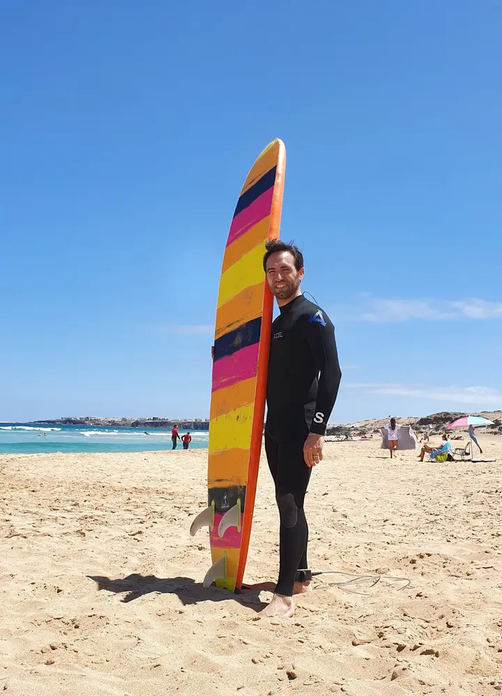 Francesco sulla spiaggia con una tavola da surf colorata